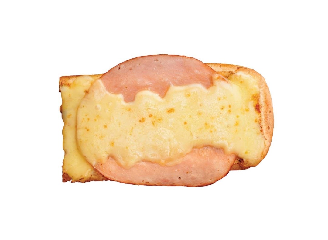 A close-up of a golden-brown toasted sandwich topped with melted cheese and slices of ham.