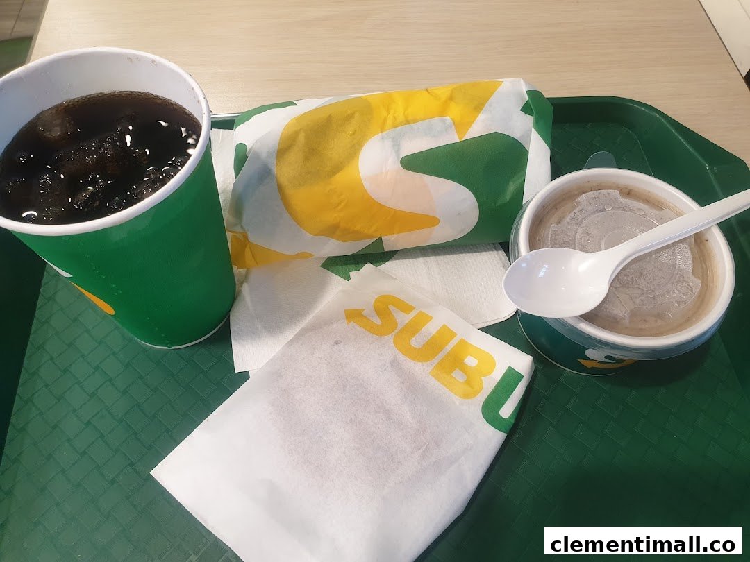 A Subway meal featuring a wrapped sandwich, a drink, and a side dish on a green tray.