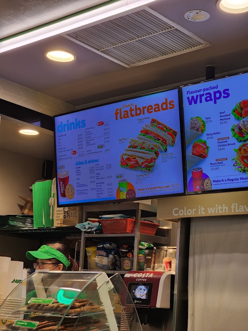 A vibrant digital menu board at Subway, showcasing flatbreads, wraps, drinks, and sides.