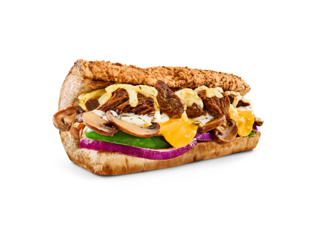 A close-up of a delicious Subway sandwich filled with meat, melted cheese, mushrooms, and fresh vegetables.
