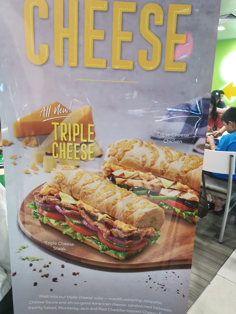 A promotional poster for Subway's new Triple Cheese subs, featuring Triple Cheese Steak and Chicken.