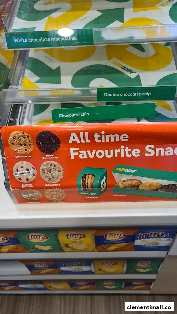 Subway's display case featuring various cookies like chocolate chip and macadamia, alongside popular chip brands.