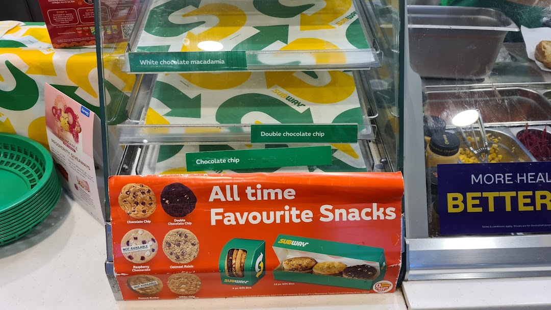 A display case at Subway featuring cookies, snacks, and fresh sandwich ingredients.