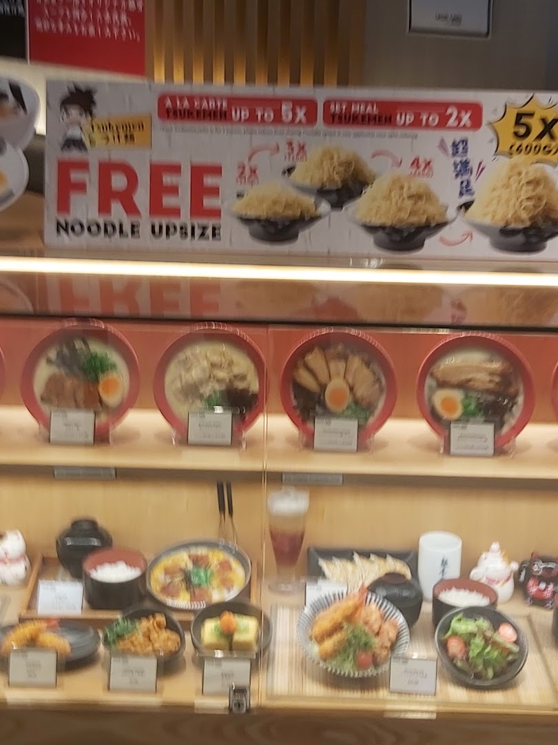 A display of realistic Japanese food models, including noodle dishes and sides, with a promotional banner.