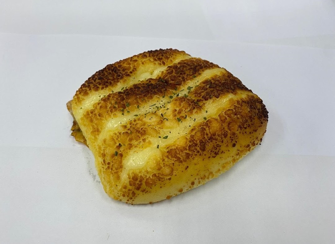 A golden-brown cheese bun with visible cheese pockets and green herbs.