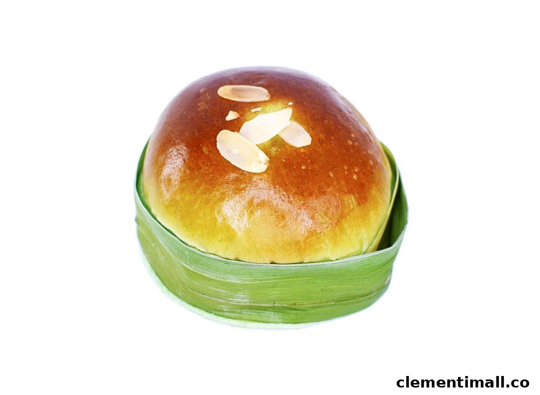 A golden-brown bun topped with almond flakes, served in a green pandan leaf wrapper.