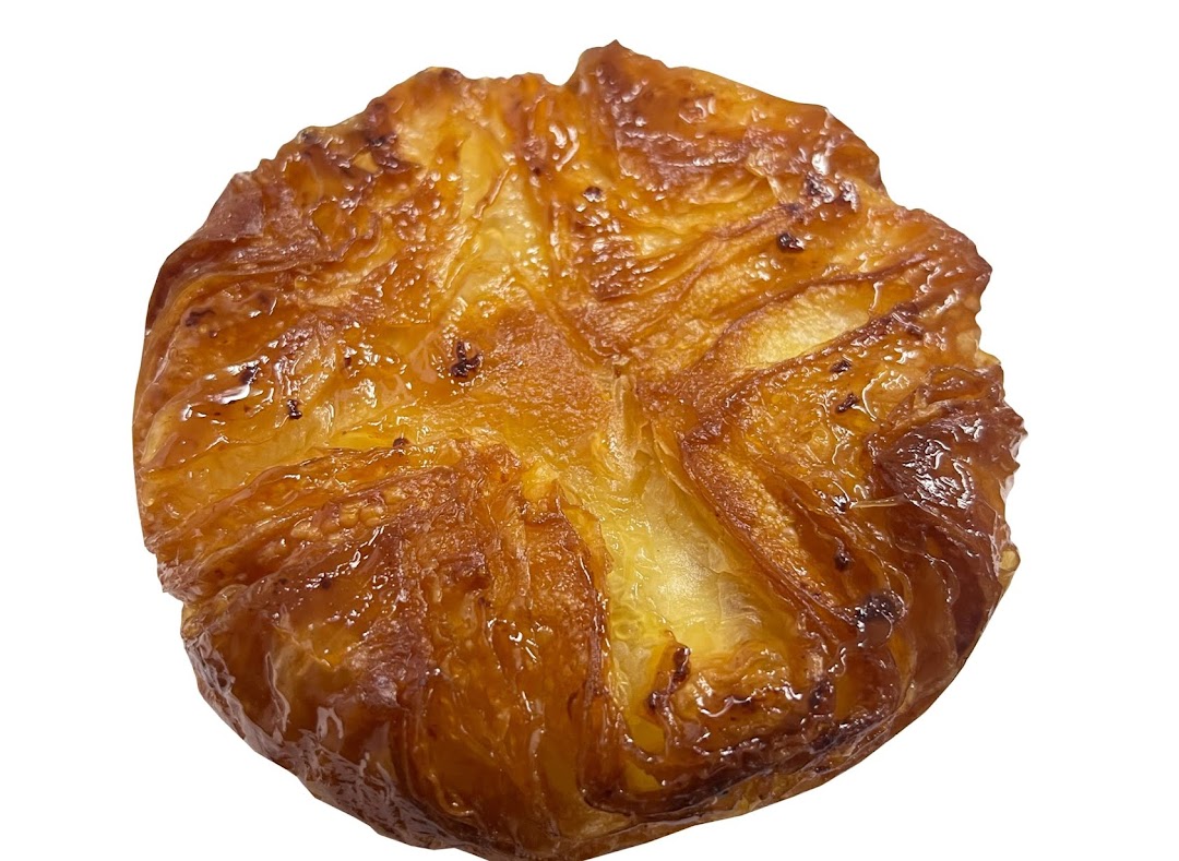 A close-up of a golden-brown, flaky pastry with a sweet, glazed finish.