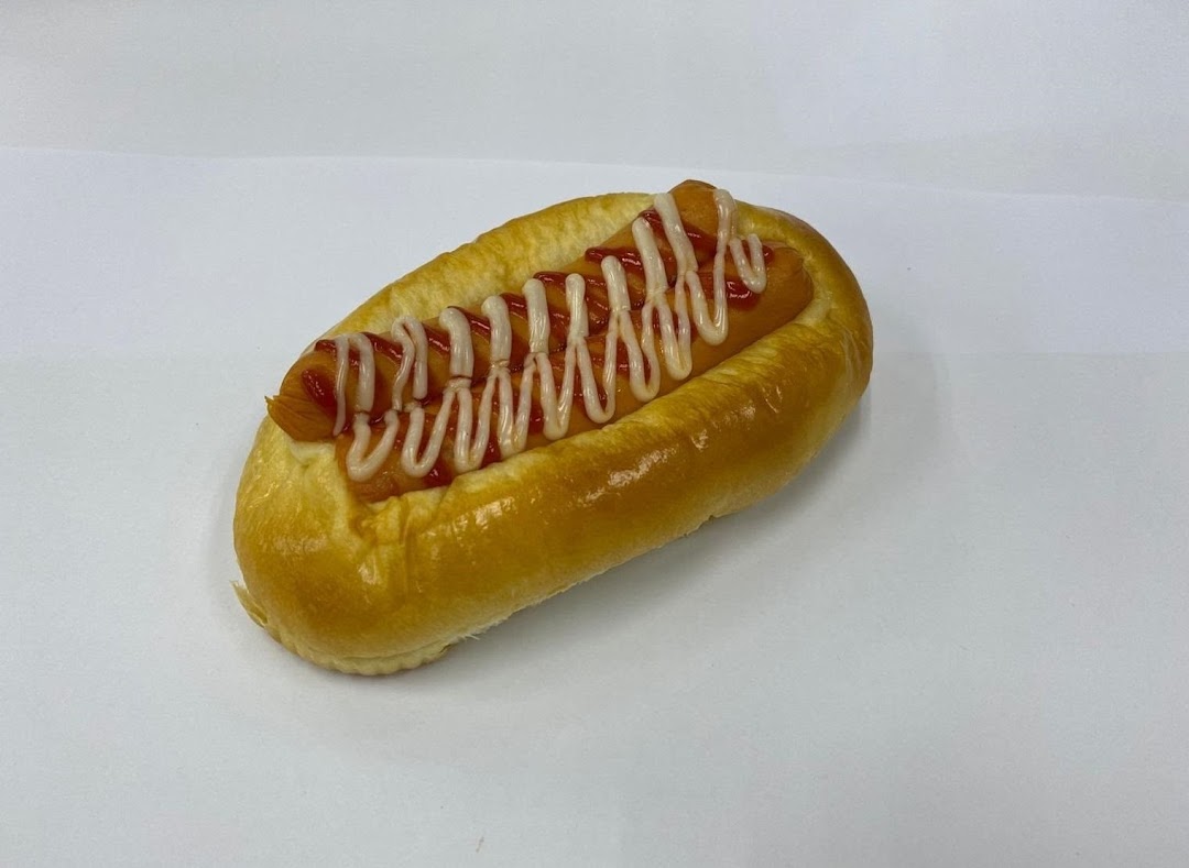 A classic hot dog bun with sausage, ketchup, and mayonnaise on a white background.