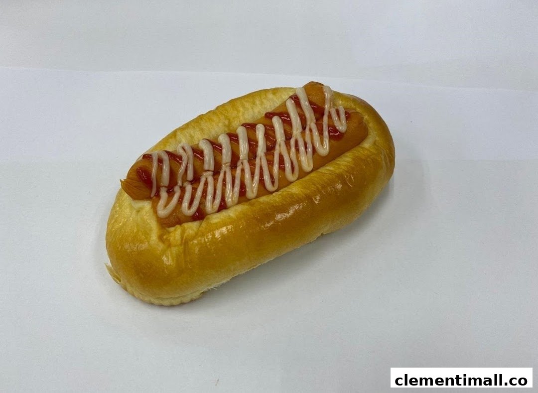 A classic hot dog bun with sausage, ketchup, and mayonnaise on a white background.