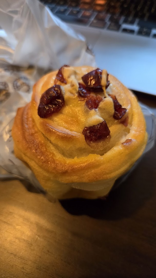 A close-up of a golden-baked pastry topped with dried cranberries.