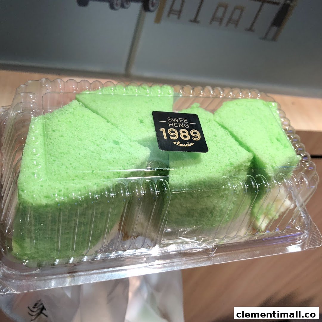 Bright green pandan cake slices in a clear plastic container with a 'Swee Heng 1989 Classic' label.