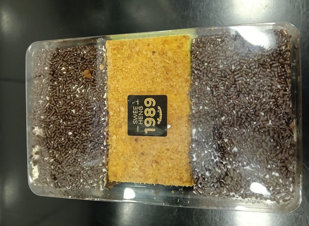 A rectangular dessert with chocolate sprinkles and a crumbly center in a clear container.