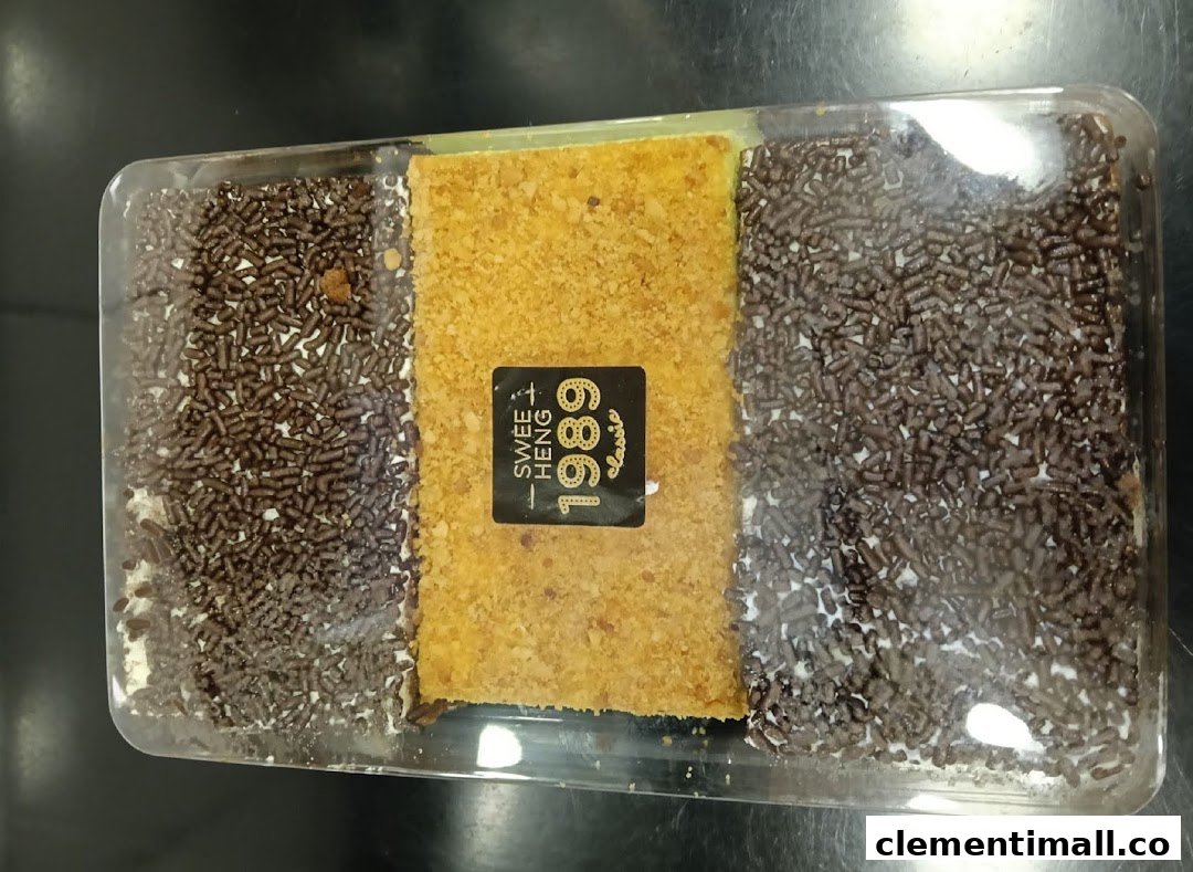 A rectangular dessert with chocolate sprinkles and a crumbly center in a clear container.