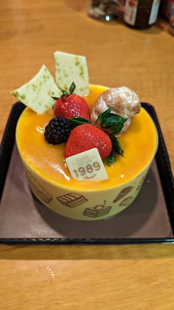 A vibrant mango cake adorned with fresh berries and white chocolate, from Swee Heng 1989 Classic.