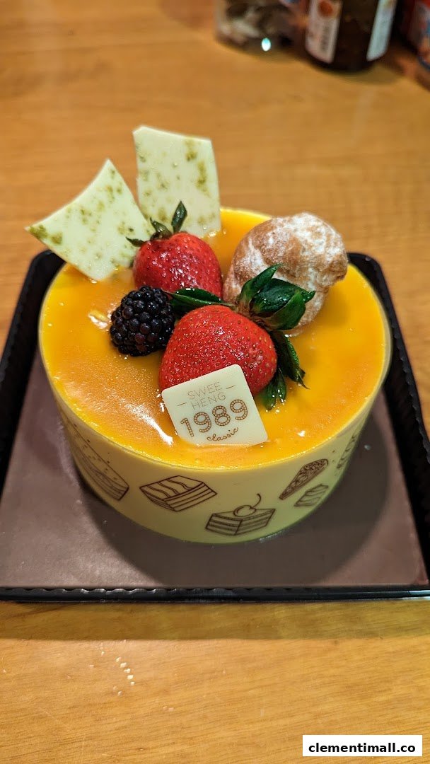 A vibrant mango cake adorned with fresh berries and white chocolate, from Swee Heng 1989 Classic.