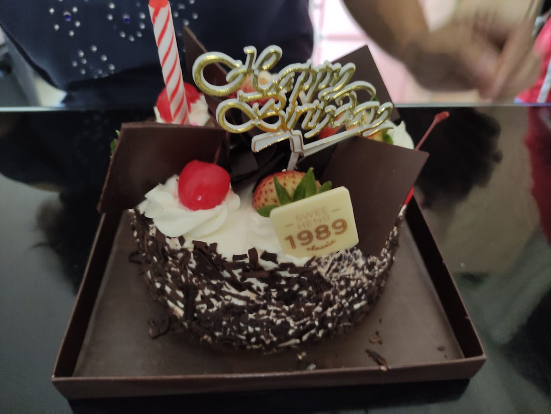 A delicious chocolate birthday cake from Swee Heng 1989 Classic, adorned with fruits and a 'Happy Birthday' topper.