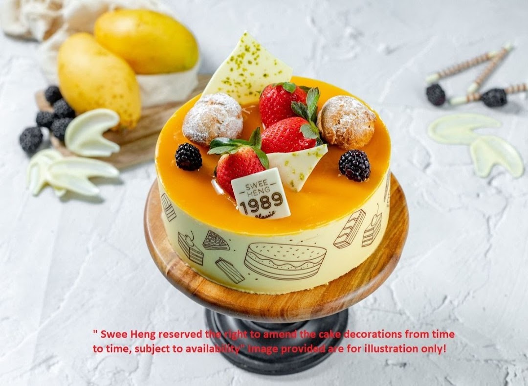 A vibrant mango-glazed cake adorned with fresh berries and pastries on a wooden stand.