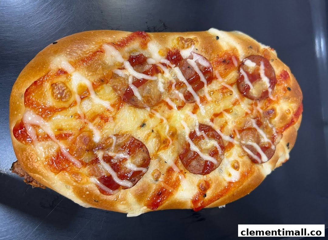 A close-up of a savory bun topped with sausage slices, cheese, and sauces.