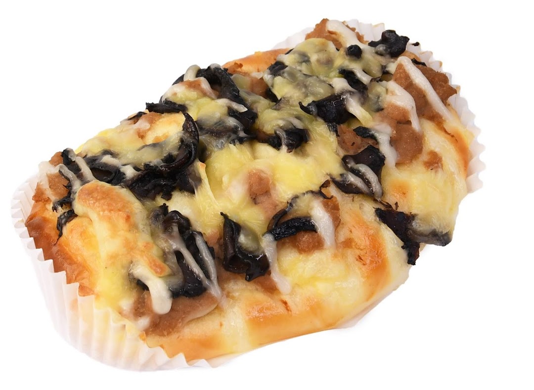 A savory bun topped with melted cheese and dark mushroom-like ingredients in a paper cup.