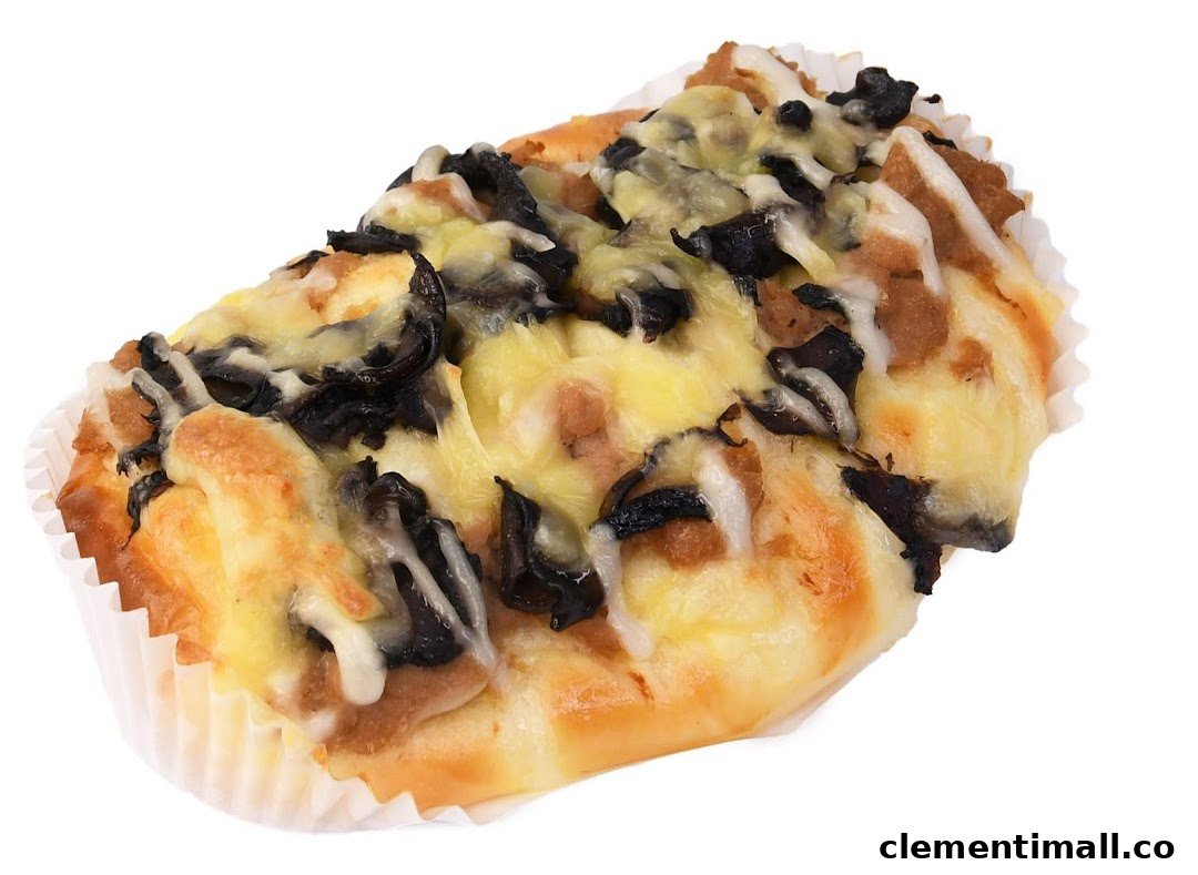 A savory bun topped with melted cheese and dark mushroom-like ingredients in a paper cup.