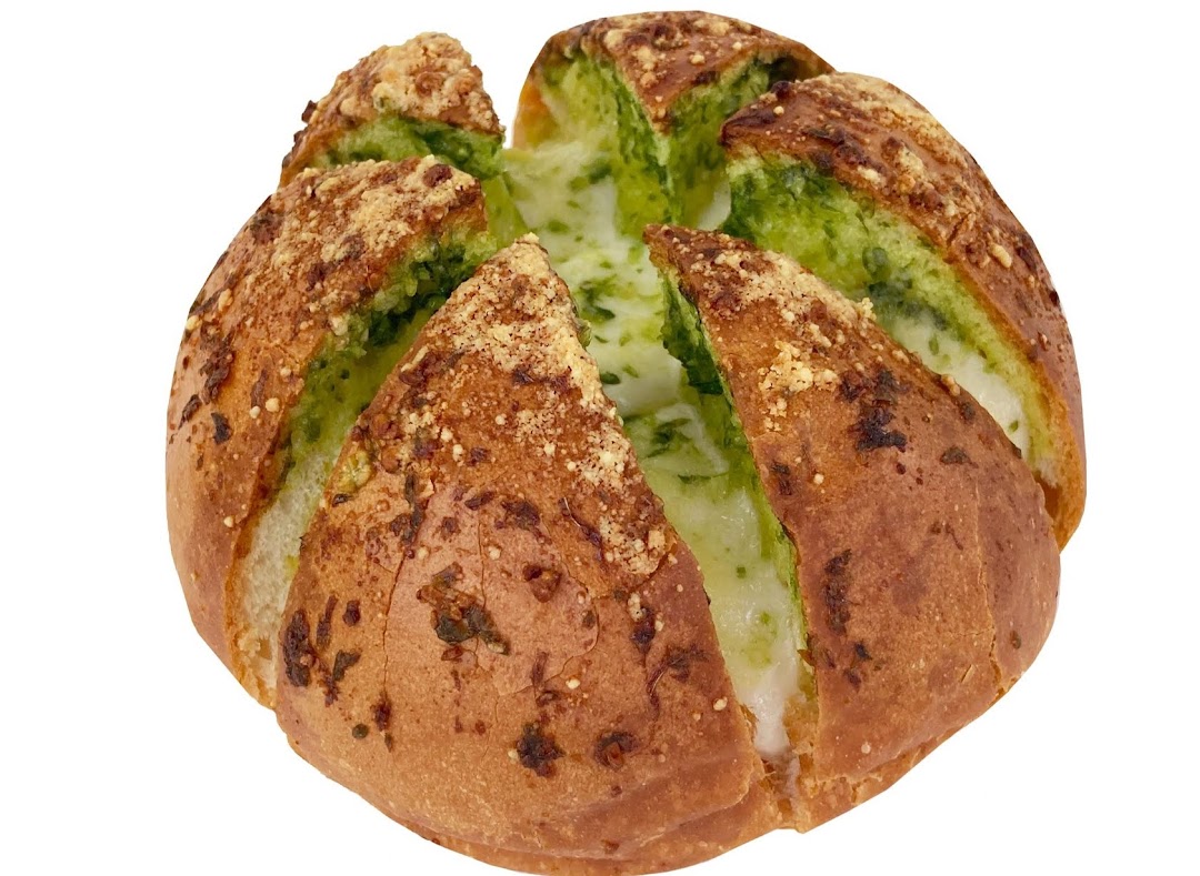 A round, golden-brown bread loaf with green pesto and melted cheese filling, topped with parmesan.