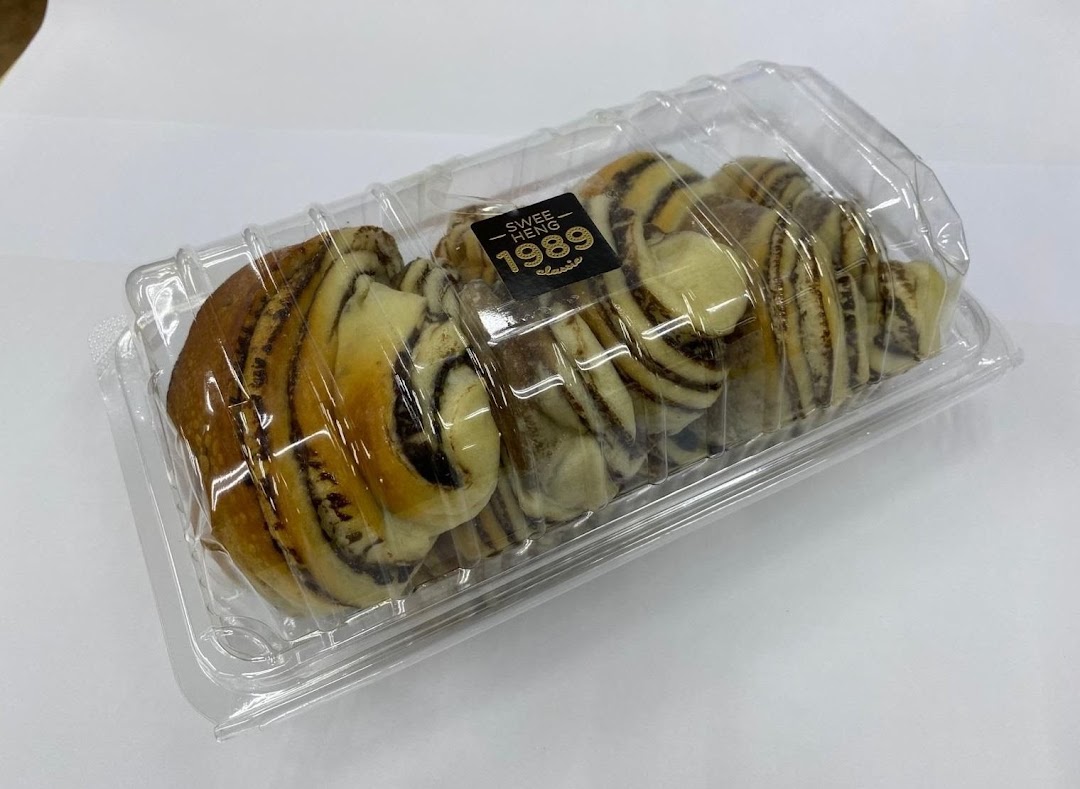 A clear plastic container holds several swirled chocolate and vanilla pastries from Swee Heng 1989 Classic.