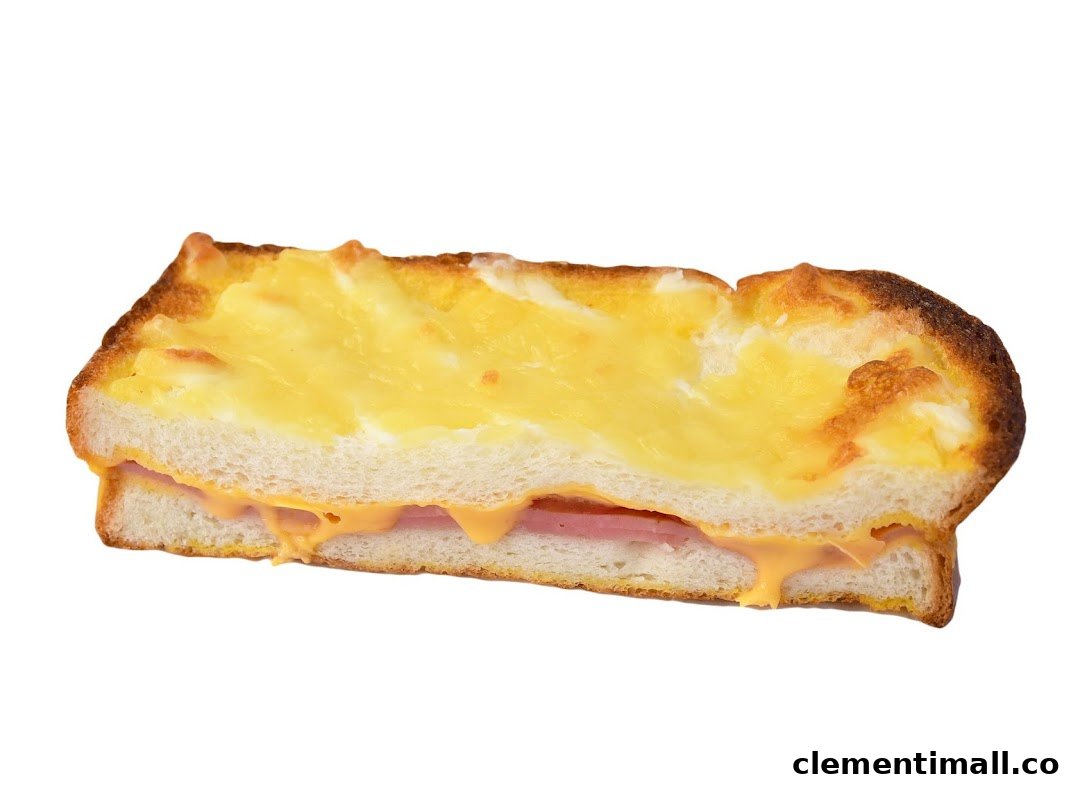 A close-up of a golden-brown baked toast with melted cheese and ham filling.