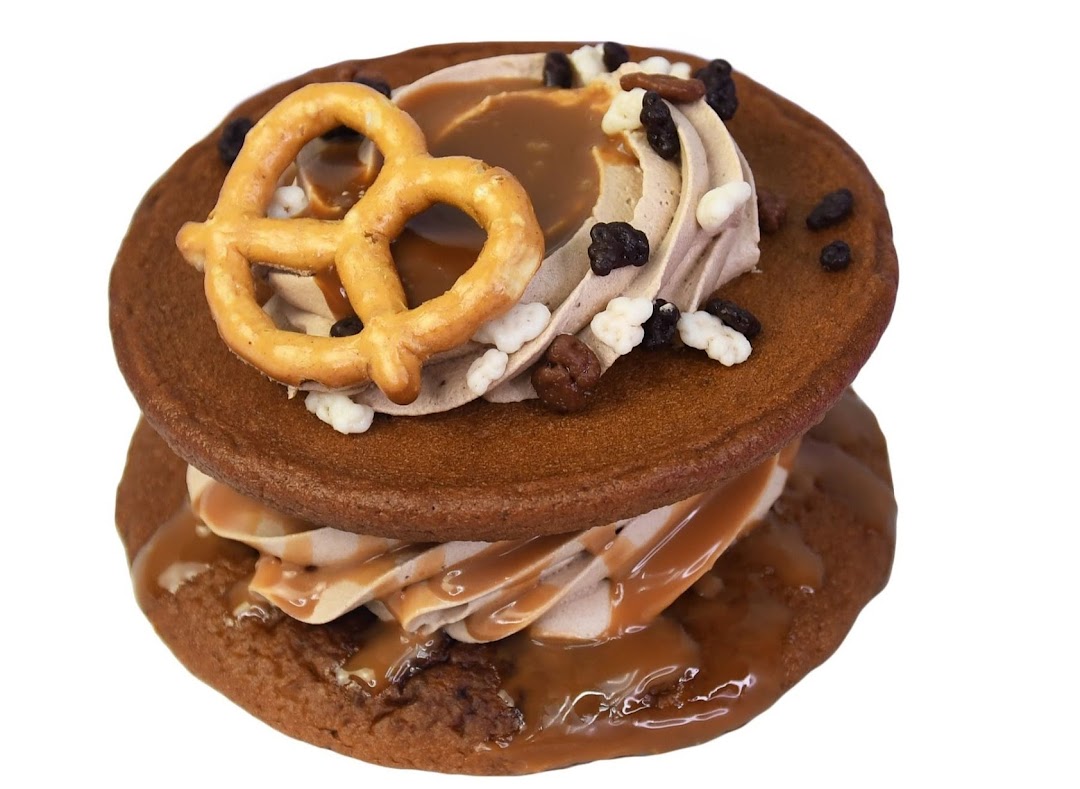 A delicious chocolate cookie sandwich with cream, caramel, and pretzel topping.