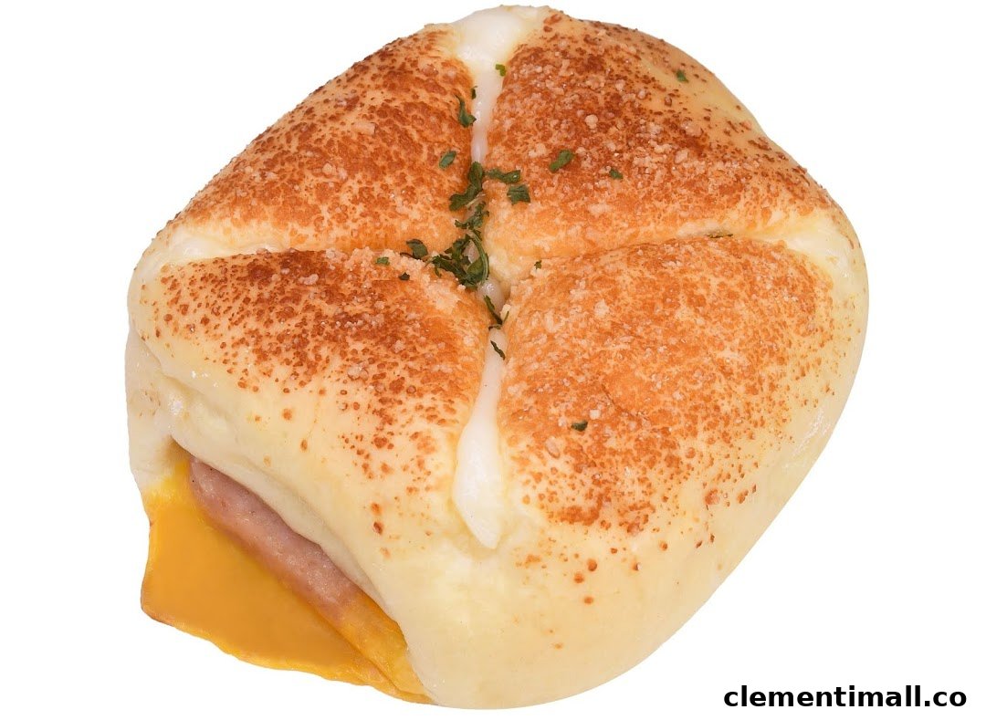 A close-up of a savory bun filled with ham and cheese, topped with crumbs and herbs.