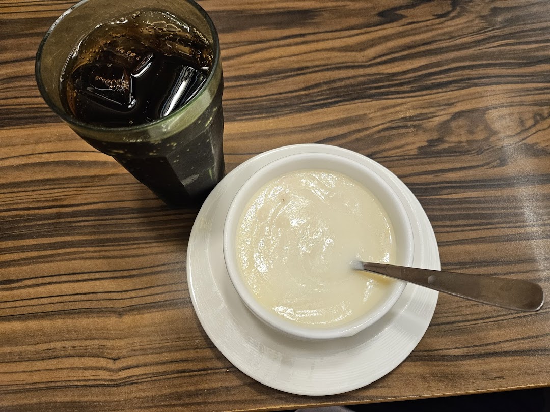 A refreshing dark beverage and a creamy dish, possibly soup or dessert, served on a wooden table.