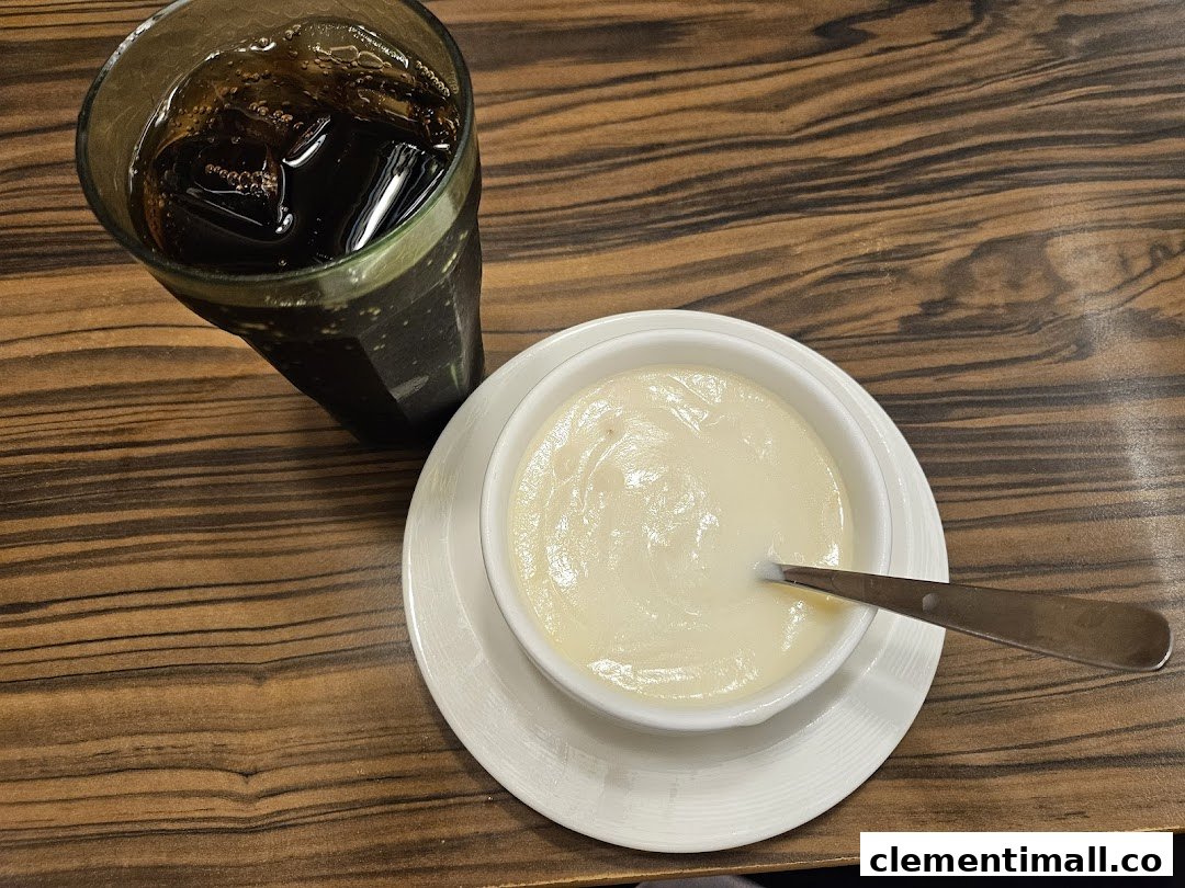 A refreshing dark beverage and a creamy dish, possibly soup or dessert, served on a wooden table.