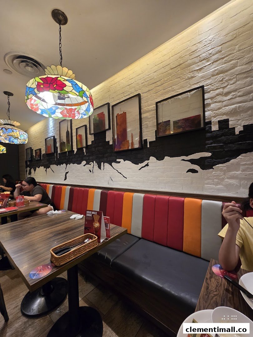 An inviting interior view of Swensen's restaurant, featuring colorful booth seating, wooden tables, and decorative lighting.