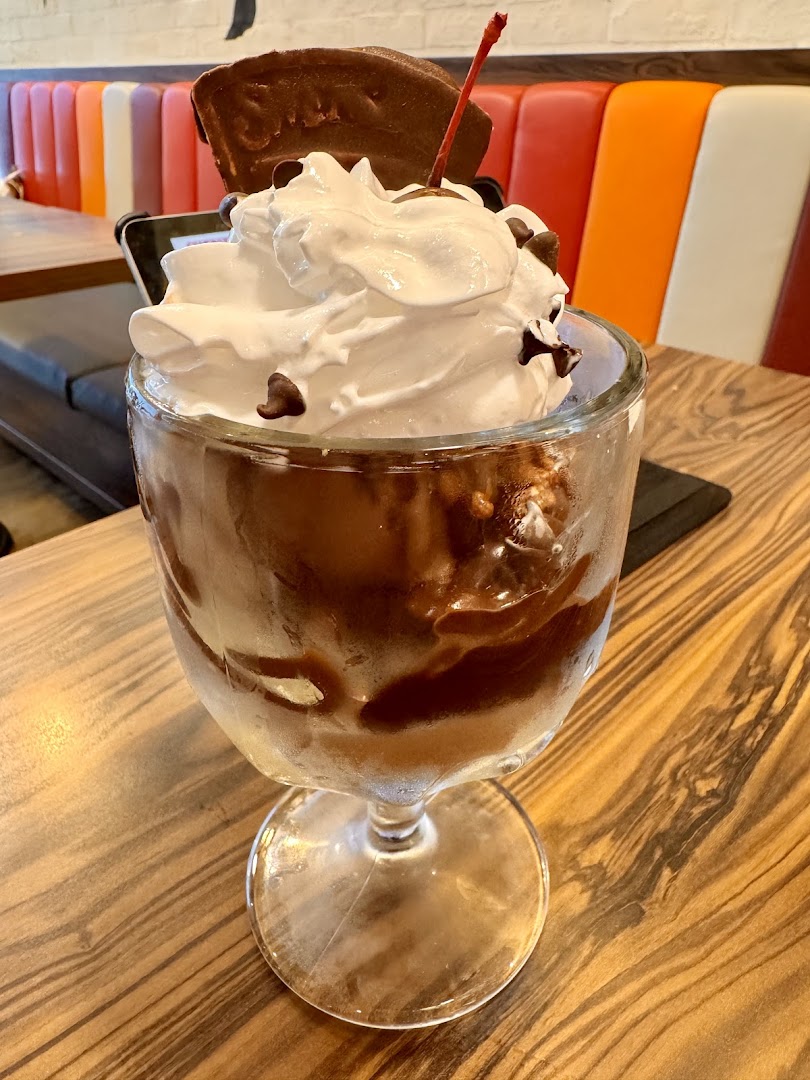A delicious chocolate sundae with whipped cream, chocolate chips, and a cherry, served at Swensen's.