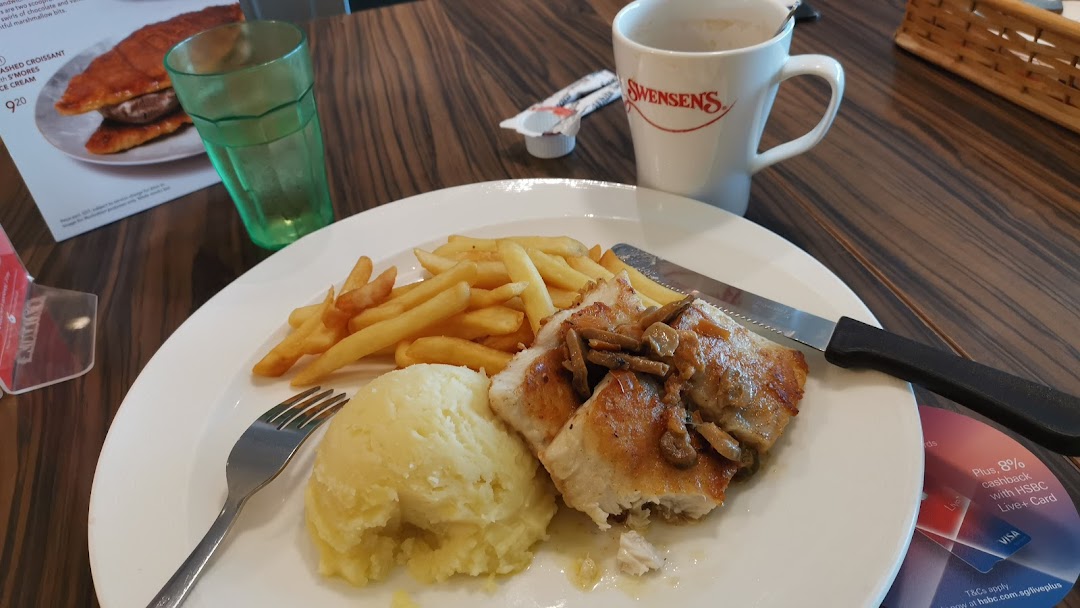 A close-up of a delicious meal with fries and mashed potatoes, a drink, and a Swensen's coffee cup.