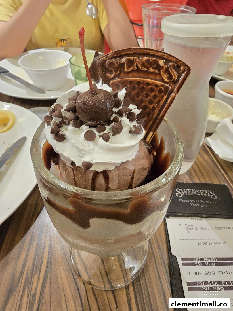 A decadent chocolate ice cream sundae with whipped cream, chocolate chips, and a cherry at Swensen's.