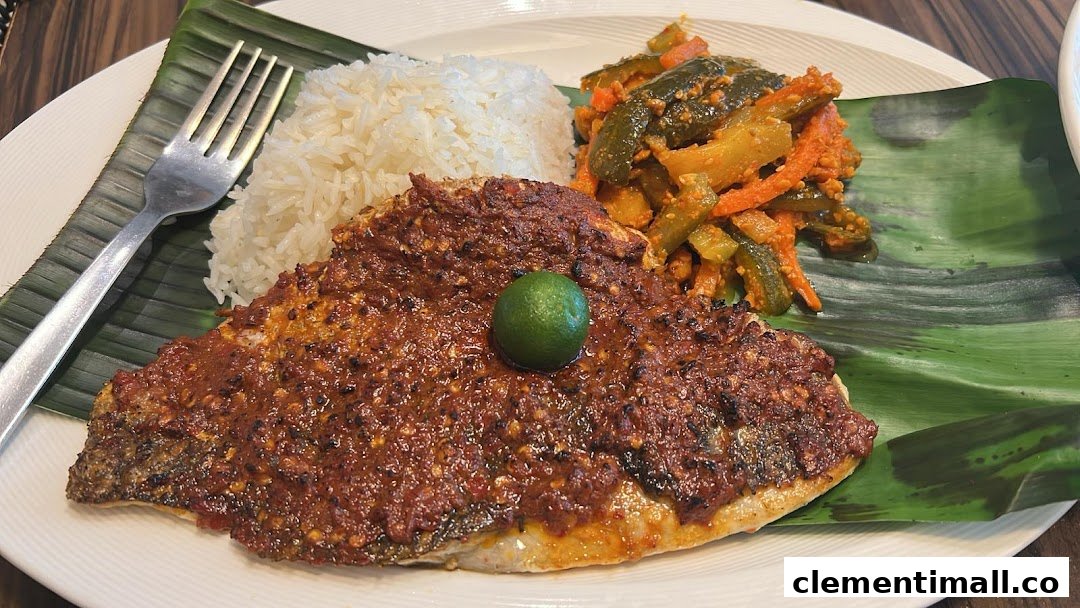 A plate of grilled fish with sambal, white rice, and pickled vegetables, served on a banana leaf.