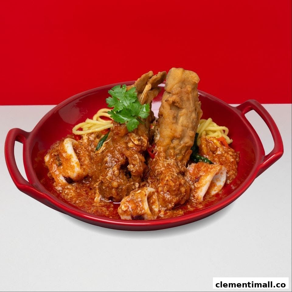 A vibrant red bowl filled with noodles, fried seafood/meat, and squid in a rich, spicy sauce, garnished with cilantro.