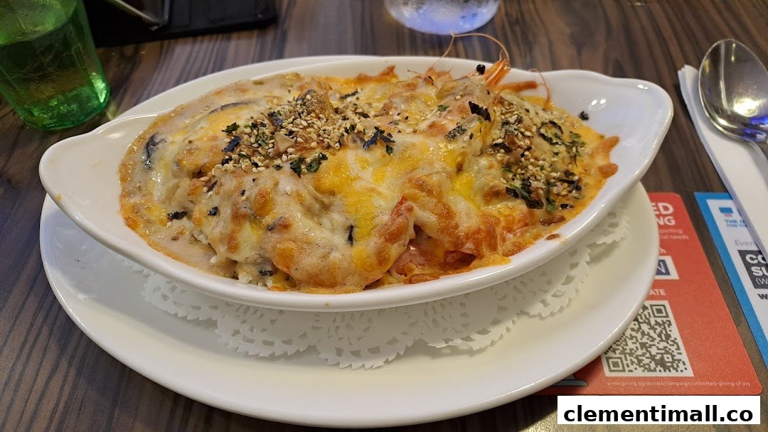 A close-up of a delicious baked cheesy seafood dish, likely with shrimp, served in a white oval bowl.
