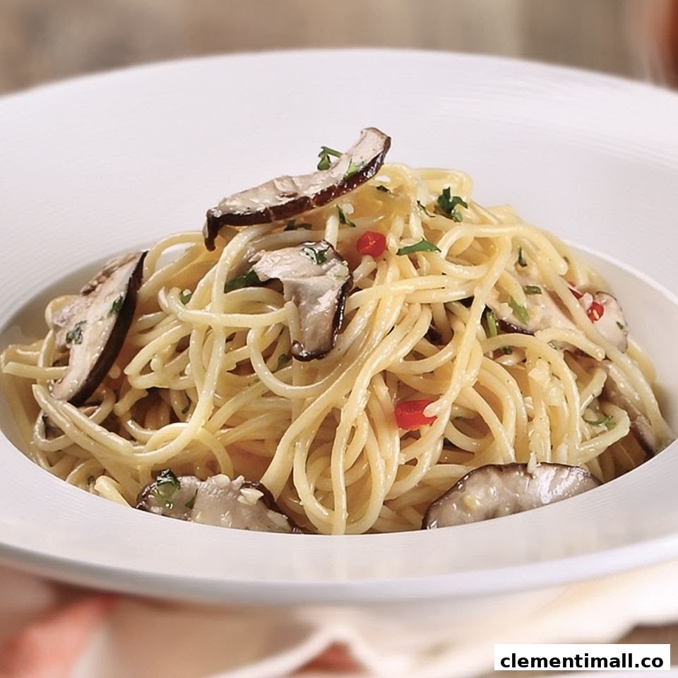A close-up of a delicious pasta dish with mushrooms, herbs, and chili flakes in a white bowl.