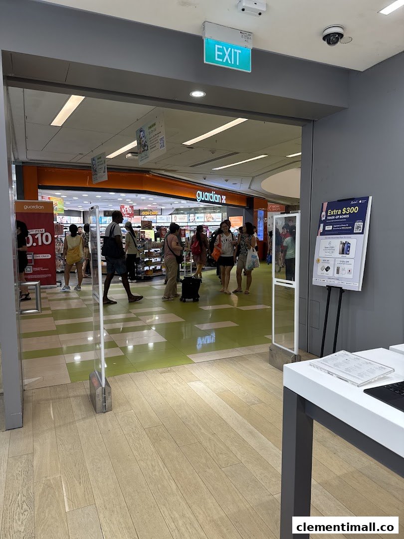 View from a retail store's exit, showing security gates and the mall corridor with shoppers and a Guardian store.