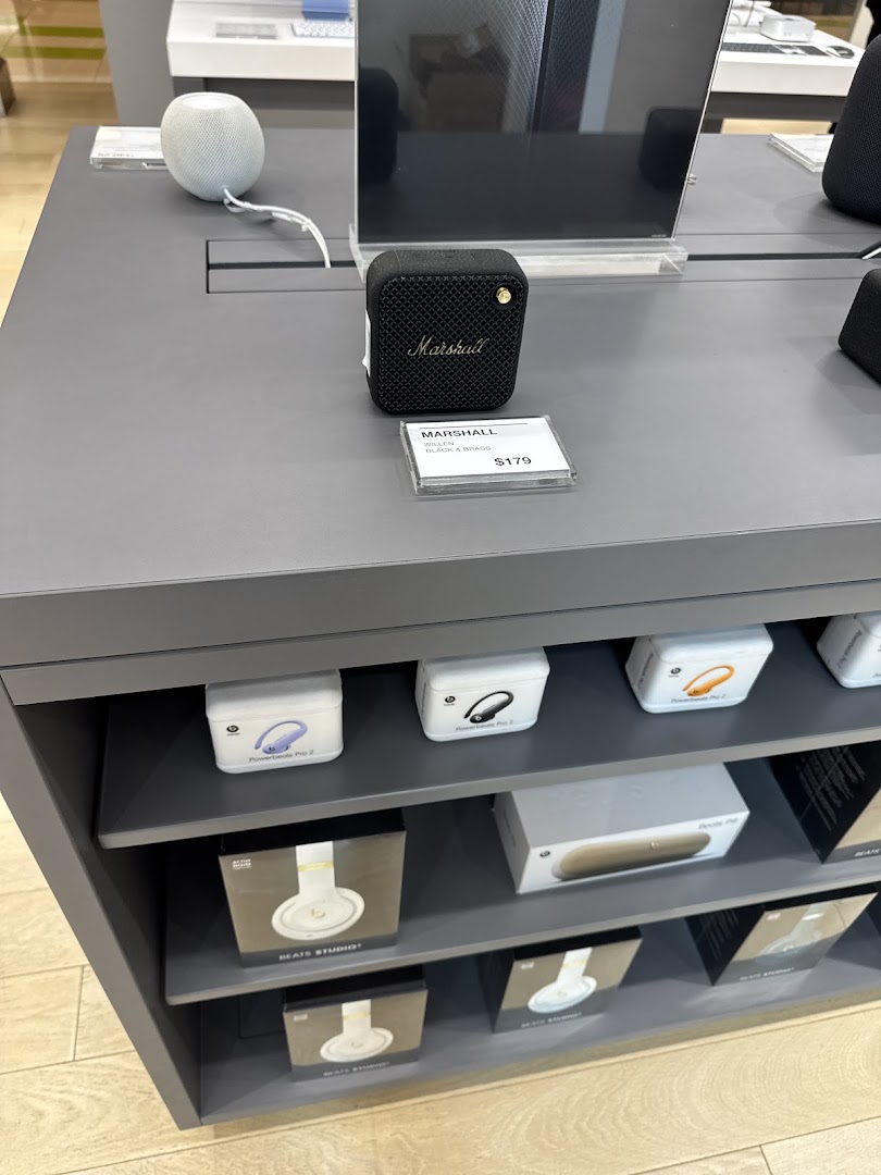 A display of Marshall speakers, Apple HomePod Mini, and various headphones in an electronics store.