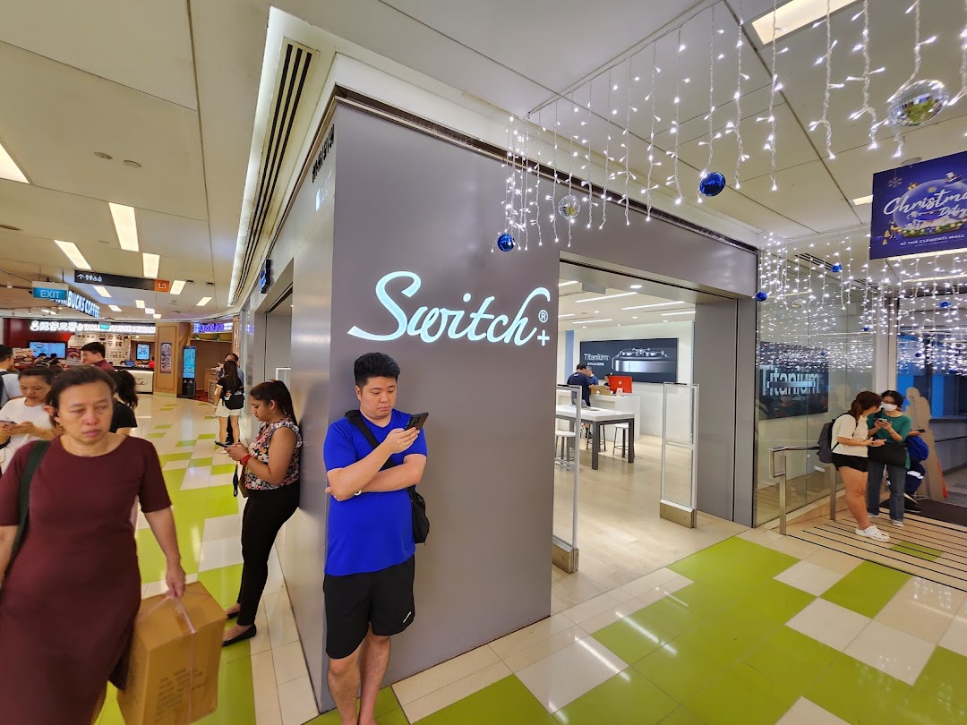 The modern entrance of Switch electronics store, adorned with festive lights, bustling with shoppers.