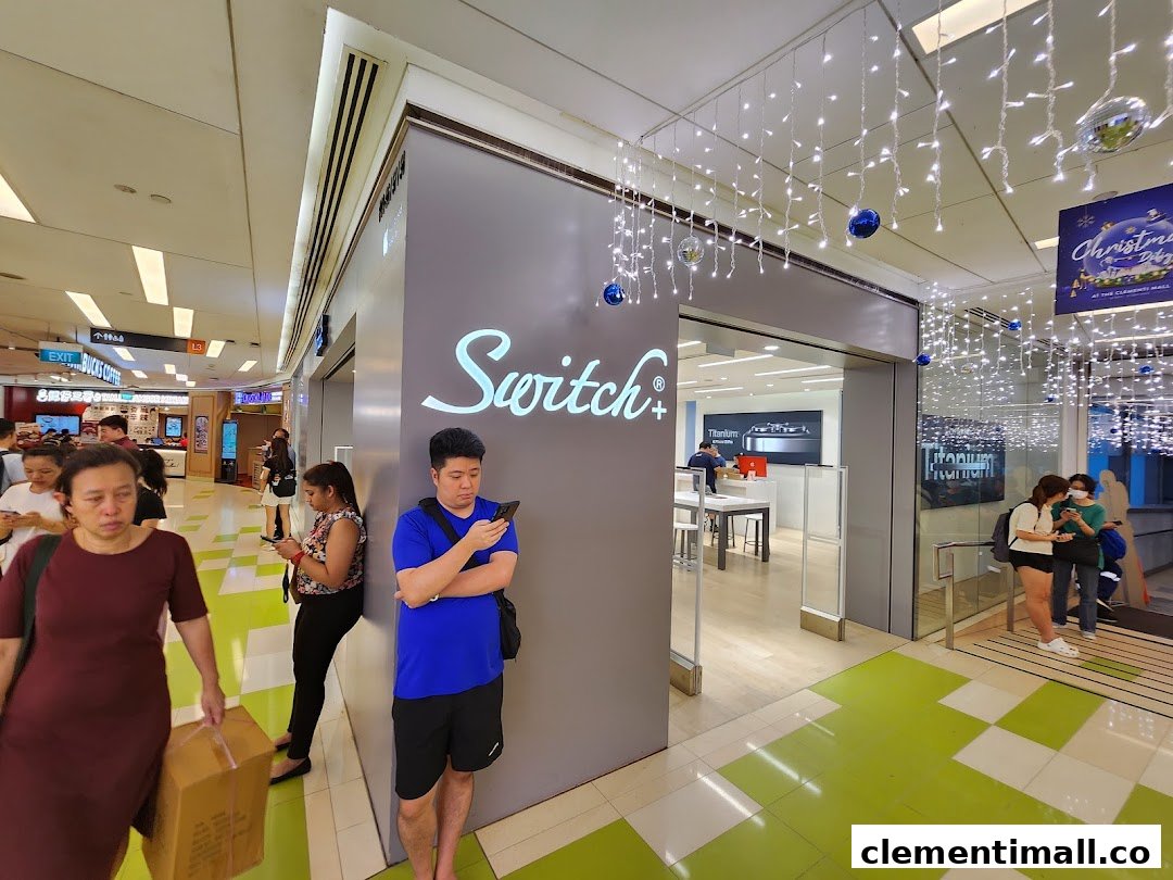 The modern entrance of Switch electronics store, adorned with festive lights, bustling with shoppers.