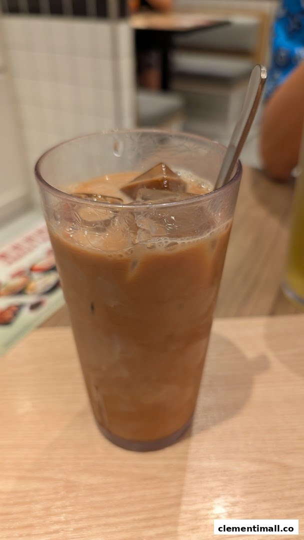 A close-up of a refreshing iced milk tea with ice cubes and a spoon on a wooden table.