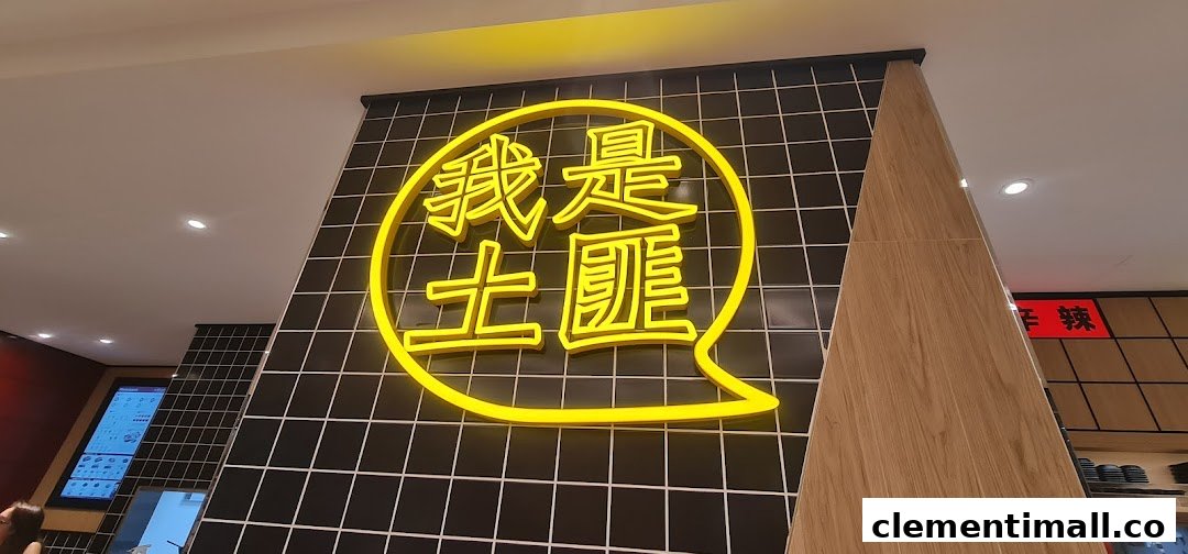 A vibrant yellow neon sign with Chinese characters '我是土匪' on a black tiled wall inside TamJai SamGor Mixian.