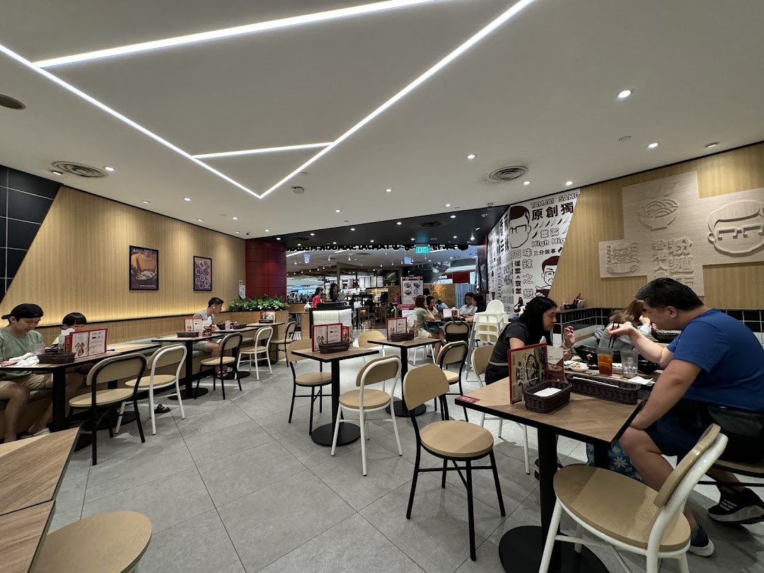 Diners enjoy a meal inside TamJai SamGor Mixian, featuring modern decor and comfortable seating.
