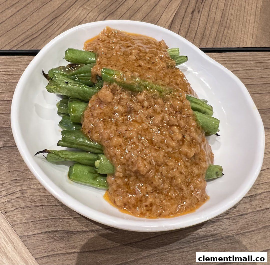 A white dish filled with green beans generously topped with a rich, savory minced meat sauce.