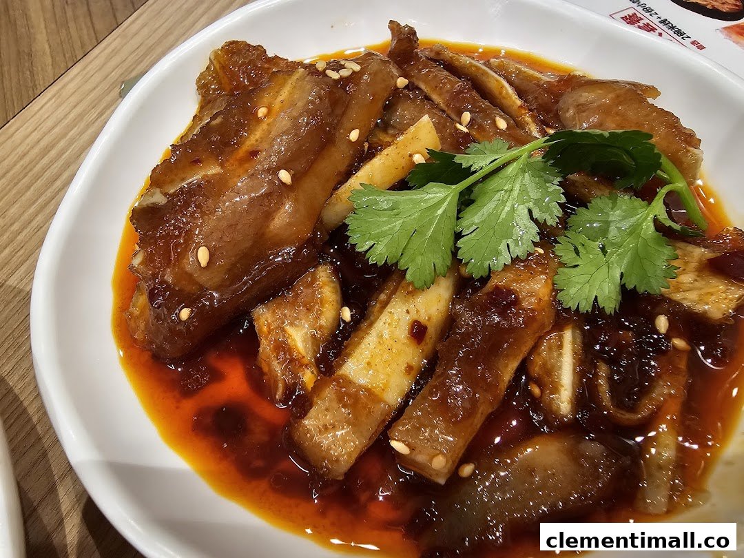 A close-up of a spicy braised dish with cilantro and sesame seeds on a white plate.