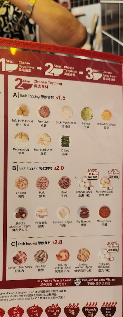 A detailed menu board displaying topping options and pricing for TamJai SamGor Mixian.
