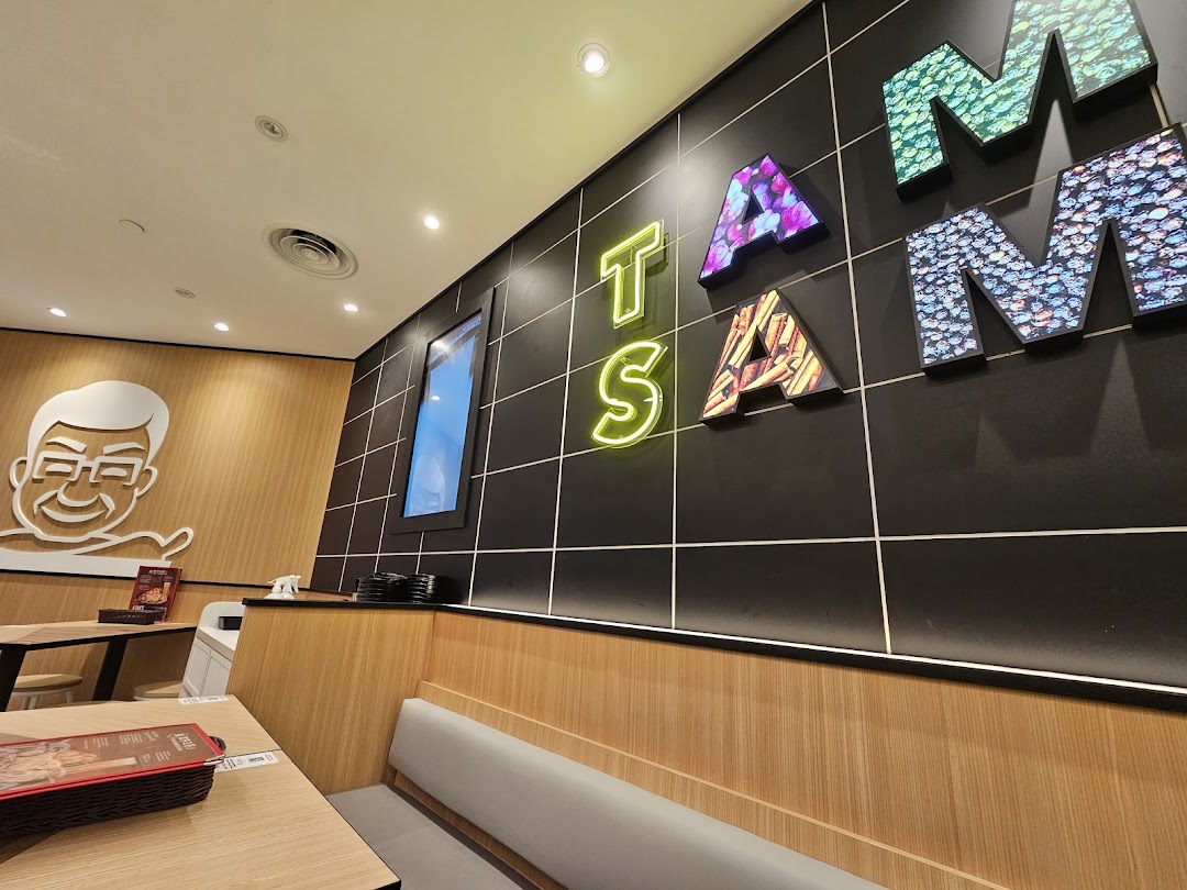 A vibrant interior shot of TamJai SamGor Mixian, featuring modern decor, comfortable seating, and illuminated wall art.